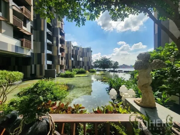 Condominium for sale in Yan Nawa, Bangkok - Riverside condominium courtyard with reflective lagoon, lush landscaping and modern facade.