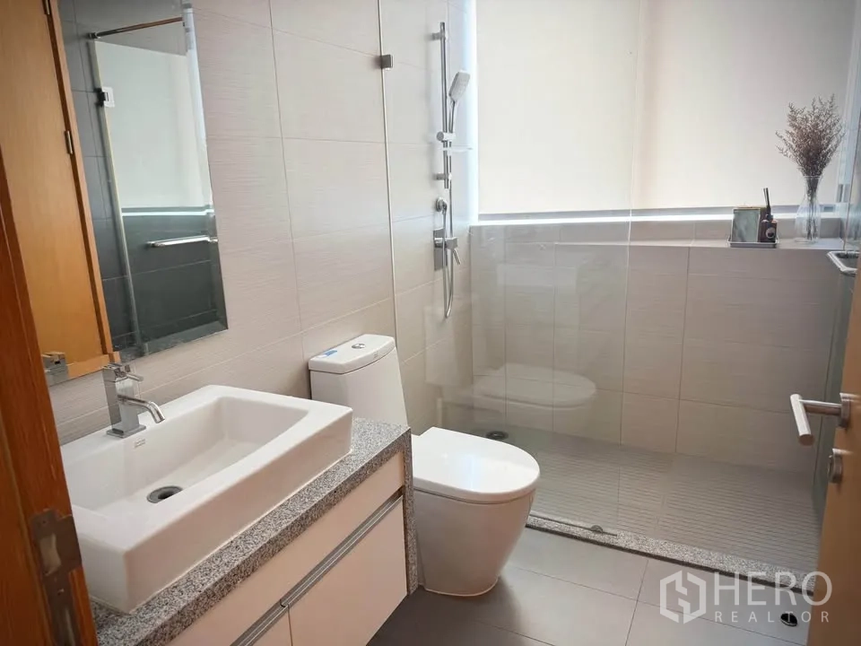คอนโด for rent or sale in Khlong Toei, Bangkok - ห้องน้ำสมัยใหม่พร้อมอ่างล้างหน้า โถสุขภัณฑ์ และตู้กระจกกั้นอาบน้ำ.