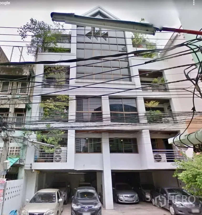 办公空间 出租在Ratchathewi, Bangkok - 城市中层办公楼，大片玻璃立面，绿植阳台与楼下遮棚停车位。