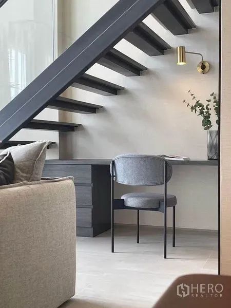 公寓 出租在Pathum Wan, Bangkok - 楼梯下的办公角，简洁书桌、灰色椅子、黄铜壁灯与开放式踏步楼梯。