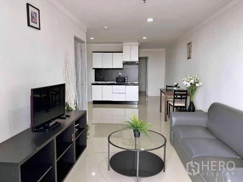 公寓 出租在Khlong Toei, Bangkok - 开放式起居区面向白色橱柜的紧凑厨房与电视柜。