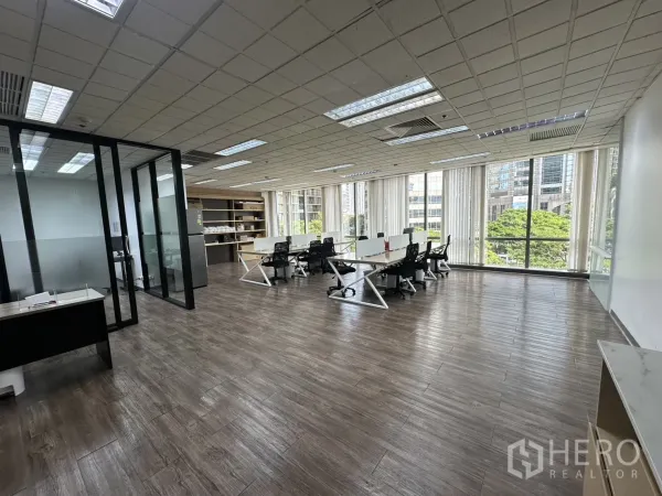 Office Space for rent - Bright open-plan office with glass meeting rooms and large windows overlooking city greenery.
