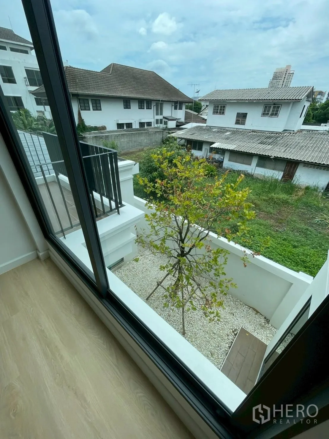 Detached House for sale in Chatuchak, Bangkok - View from window to a private courtyard garden with a tree and white pebbles.
