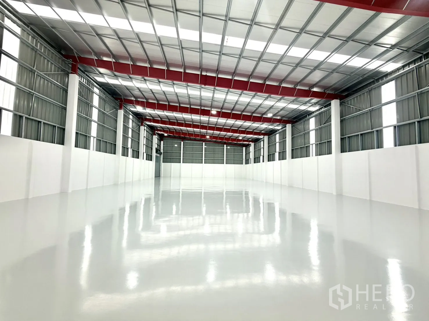 Factory for rent or sale in Lam Luk Ka, Pathum Thani - Deep view of the open production hall with skylights and epoxy flooring.