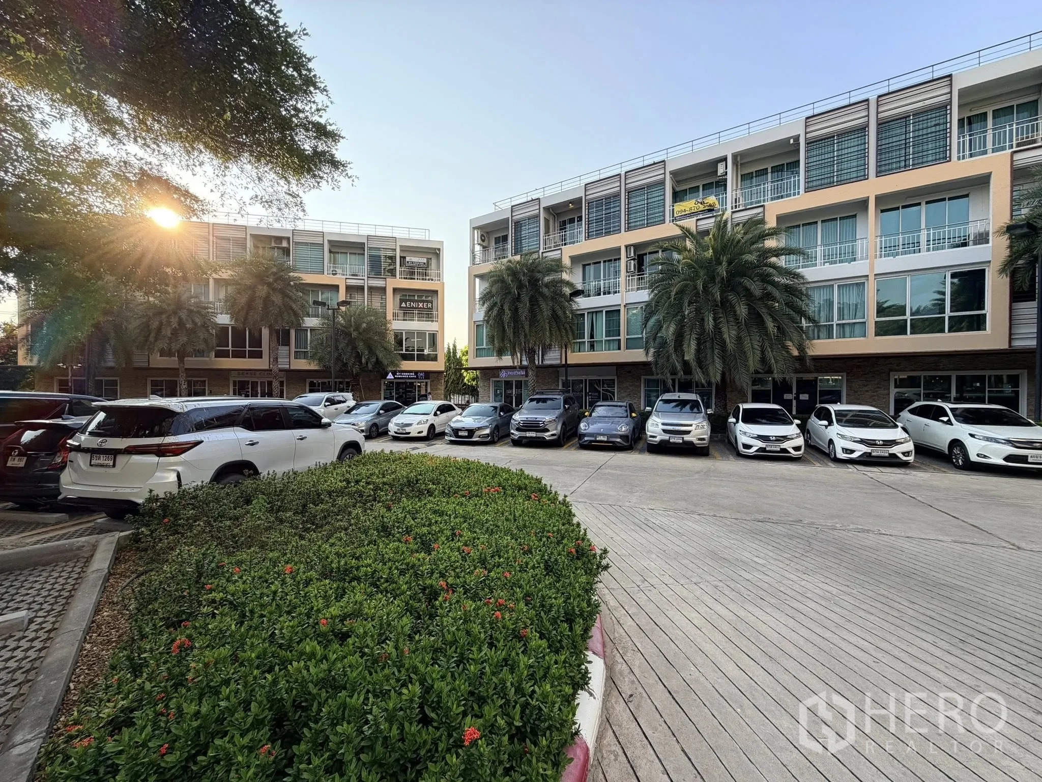 Home Office for rent or sale in Yan Nawa, Bangkok - Exterior view of a low-rise complex with palm trees and ample parking spaces.