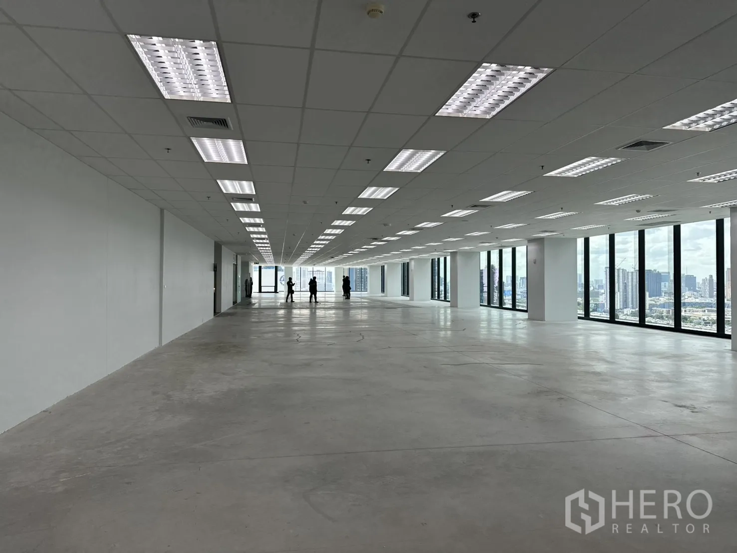 Office Space for rent in Ratchathewi, Bangkok - Expansive open-plan office with drop ceiling lights and full-height windows overlooking the city skyline.