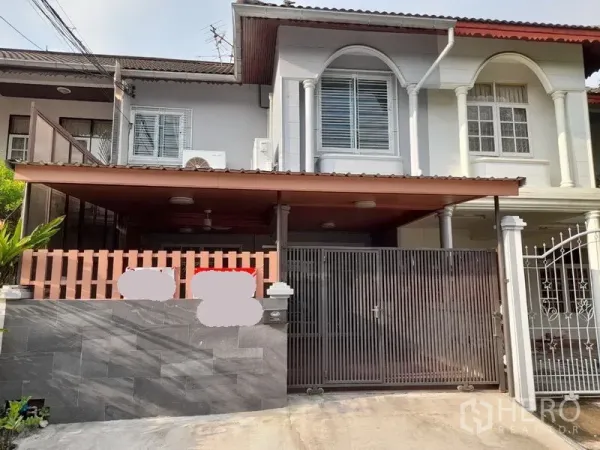 联排别墅 出租或出售 - 曼谷Huai Khwang区两层联排别墅外观，带大门与有顶车位。