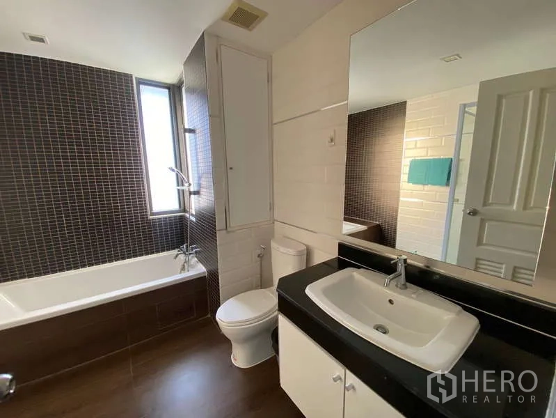 公寓 出租在Khlong Toei, Bangkok - 采光良好浴室，浴缸淋浴、超大镜面和白色洗手台。