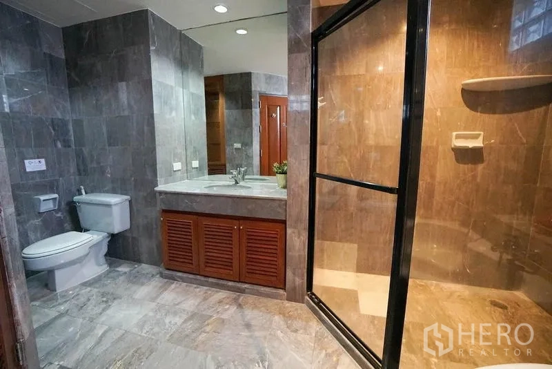 อพาร์ทเมนท์ ให้เช่าในWatthana, Bangkok - ห้องน้ำตกแต่งหินอ่อน เคาน์เตอร์กว้าง โถสุขภัณฑ์ และตู้ฝักบัวกระจก