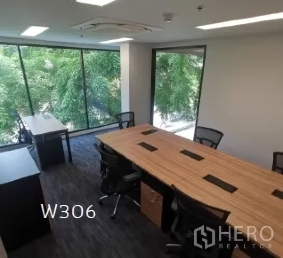 Office Space for rent in Khlong Toei, Bangkok - Private office with long workstations, dark carpet, and floor-to-ceiling windows overlooking green trees.