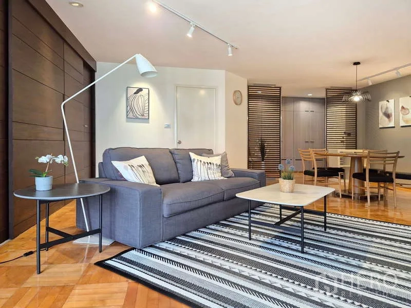 Condominium for rent in Yan Nawa, Bangkok - Open-plan living and dining with gray sofa, coffee table and striped rug.