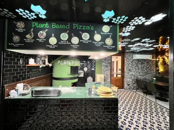 อาคารพาณิชย์ ให้เช่าในWatthana, Bangkok - เคาน์เตอร์พิซซ่าแบบเปิด เตาอบกรุโมเสกสีเขียว กระเบื้องสีดำ และป้ายเมนูเหนือเคาน์เตอร์.