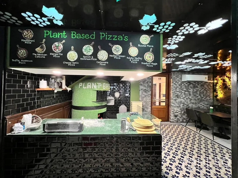 อาคารพาณิชย์ ให้เช่าในWatthana, Bangkok - เคาน์เตอร์พิซซ่าแบบเปิด เตาอบกรุโมเสกสีเขียว กระเบื้องสีดำ และป้ายเมนูเหนือเคาน์เตอร์.