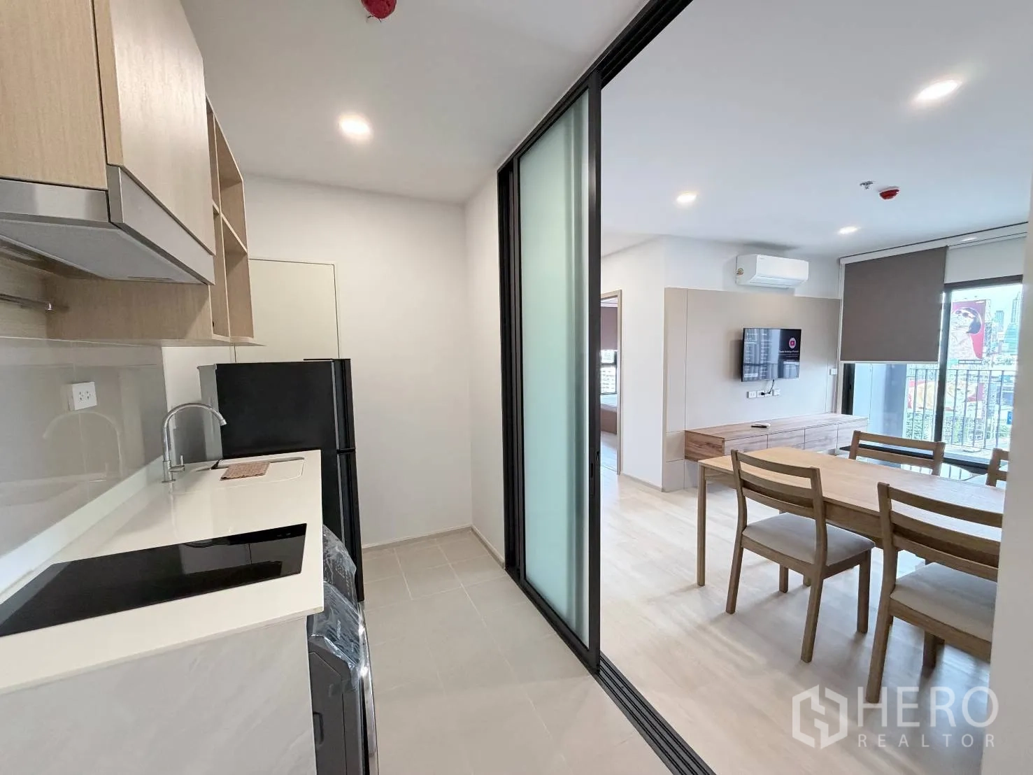 คอนโด for rent in Din Daeng, Bangkok - ครัวกั้นด้วยกระจกบานเลื่อน มองออกไปยังโต๊ะอาหารและห้องนั่งเล่นที่มีทีวี