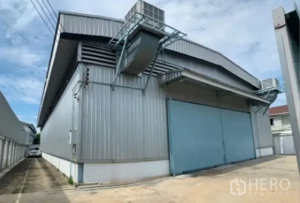Warehouse for rent in Suan Luang, Bangkok - Front angle of corrugated metal warehouse with wide entry doors and open loading area.