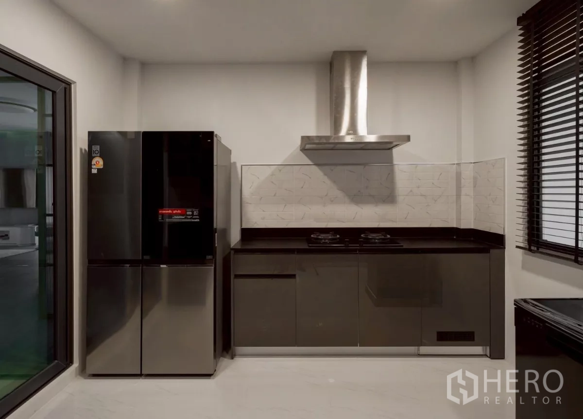 Detached House for rent in Bang Phli, Samut Prakan - Secondary kitchen with black countertops, a large fridge and range hood