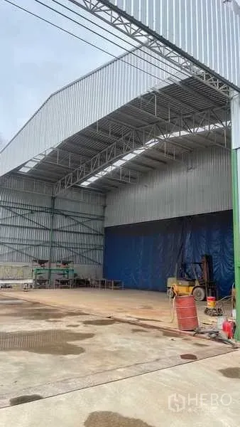 工厂 出售在Nikhom Phatthana, Rayong - 高挑挑檐装卸区，宽大出入口，内有叉车与工业油桶。