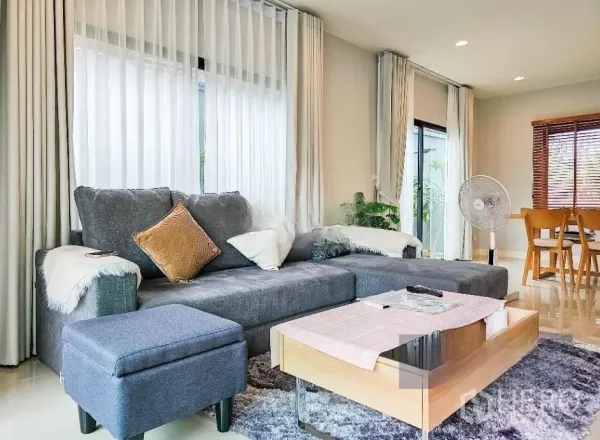 บ้าน ขายในLam Luk Ka, Pathum Thani - ห้องนั่งเล่นสว่าง โซฟาเข้ามุมสีเทา ผ้าม่านโปร่ง และโต๊ะกาแฟไม้