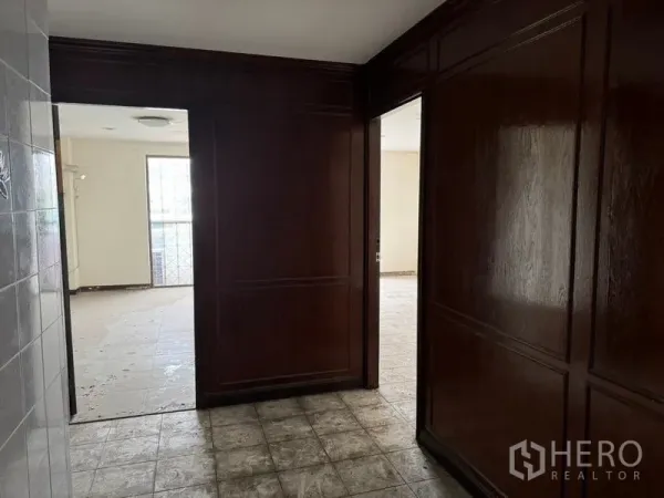 Shophouse for rent in Watthana, Bangkok - Hallway with dark wood paneled walls connecting to bright rooms.