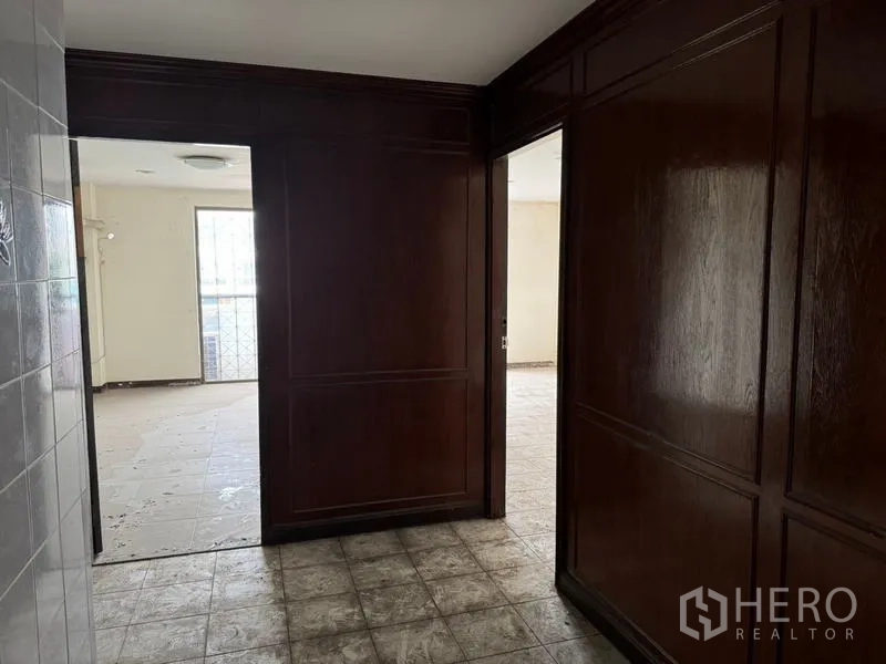 Shophouse for rent in Watthana, Bangkok - Hallway with dark wood paneled walls connecting to bright rooms.