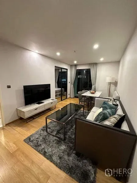 公寓 出租在Pathum Wan, Bangkok - 客厅朝向阳台，配电视与餐桌，大窗采光佳