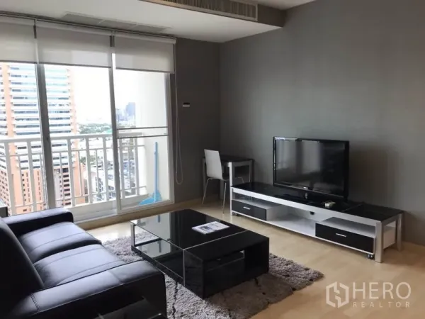 คอนโด ให้เช่าหรือขายในWatthana, Bangkok - มุมทีวีพร้อมโซฟาหนังสีดำและหน้าต่างสูงจรดเพดานออกสู่ระเบียง