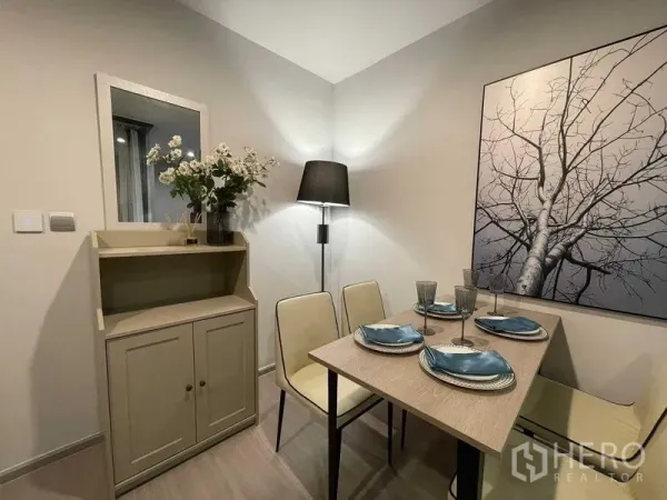 公寓 出租在Chatuchak, Bangkok - 温馨用餐角落，墙面装饰画、边柜与落地灯。