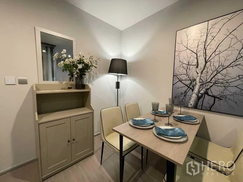 公寓 出租在Chatuchak, Bangkok - 温馨用餐角落，墙面装饰画、边柜与落地灯。