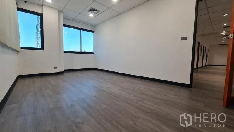 Office Space for rent in Watthana, Bangkok - Long private room with windows, white walls and wood-look floors.