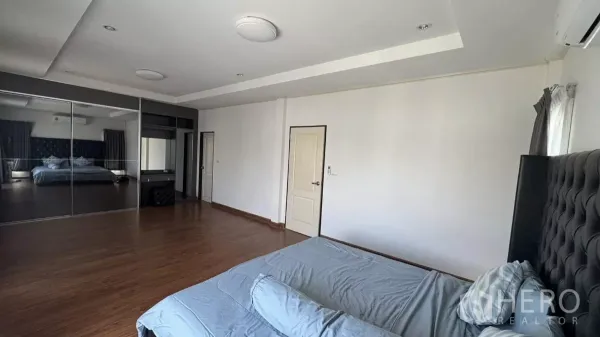 บ้าน ขายในLat Krabang, Bangkok - ห้องนอนใหญ่กว้าง พื้นไม้ หัวเตียงบุผ้า และตู้เสื้อผ้าบานกระจก