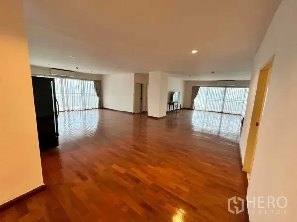 公寓 出租在Bangkok - 宽阔客厅，两侧落地窗与光亮木地板