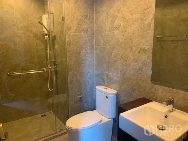Condominium for rent in Watthana, Bangkok - Modern bathroom with glass-enclosed shower, toilet and square vanity sink.
