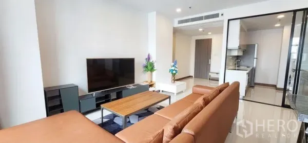 Condominium for rent - Open-plan lounge facing a large flat-screen TV with a glass-partitioned kitchen beyond.