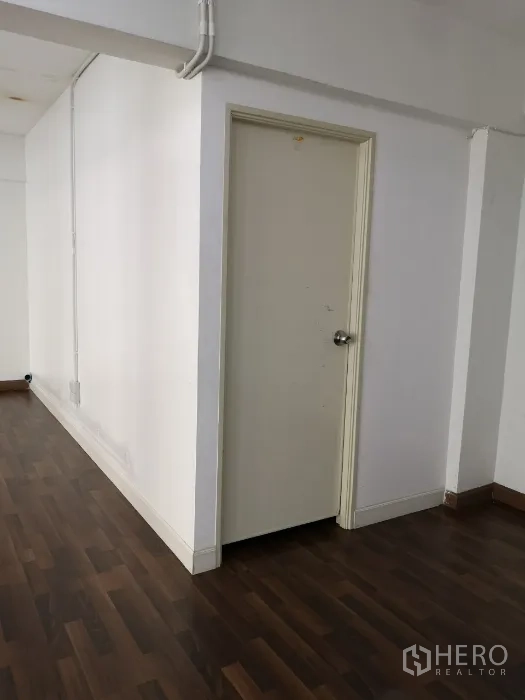 Office Space for rent in Khlong Toei, Bangkok - Interior corner with white door to bathroom and exposed electrical conduit.