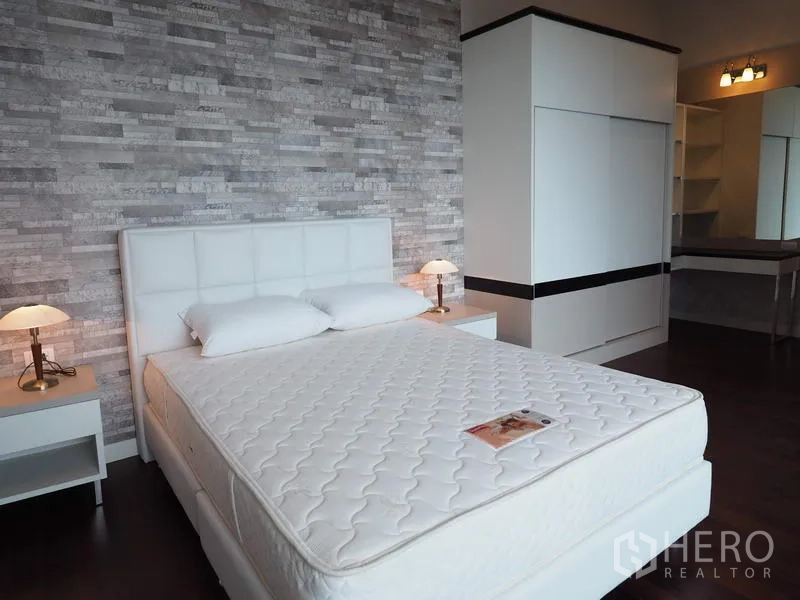Condominium for rent in Ratchathewi, Bangkok - Spacious guest bedroom with white headboard, built-in wardrobe and dressing area.