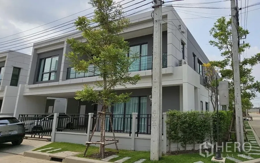 Detached House for rent in Bang Phli, Samut Prakan - Corner exterior view of the contemporary house with fenced garden and driveway.
