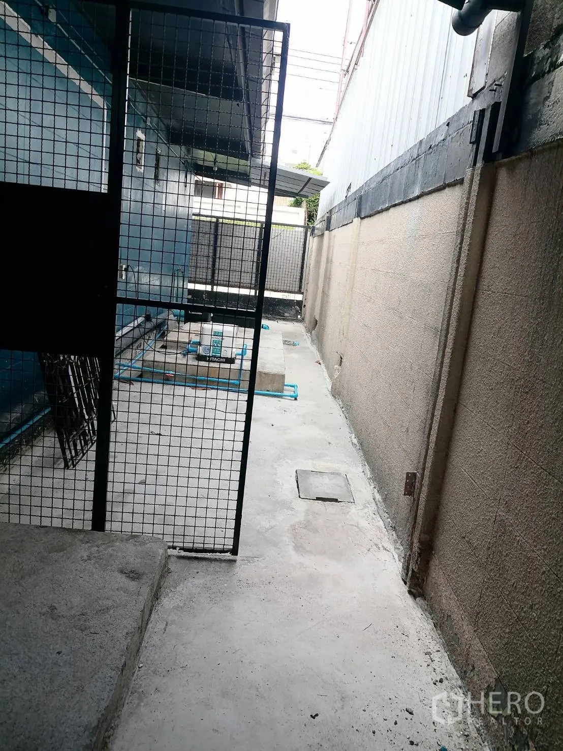 Detached House for rent in Watthana, Bangkok - Side service corridor with a metal gate and maintenance piping along the wall.