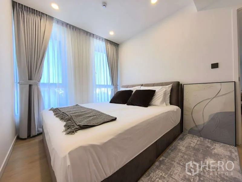 อพาร์ทเมนท์ ให้เช่า - ห้องนอนอบอุ่น เตียงคู่ หน้าต่างเต็มบานและผ้าม่านทึบสีเทา