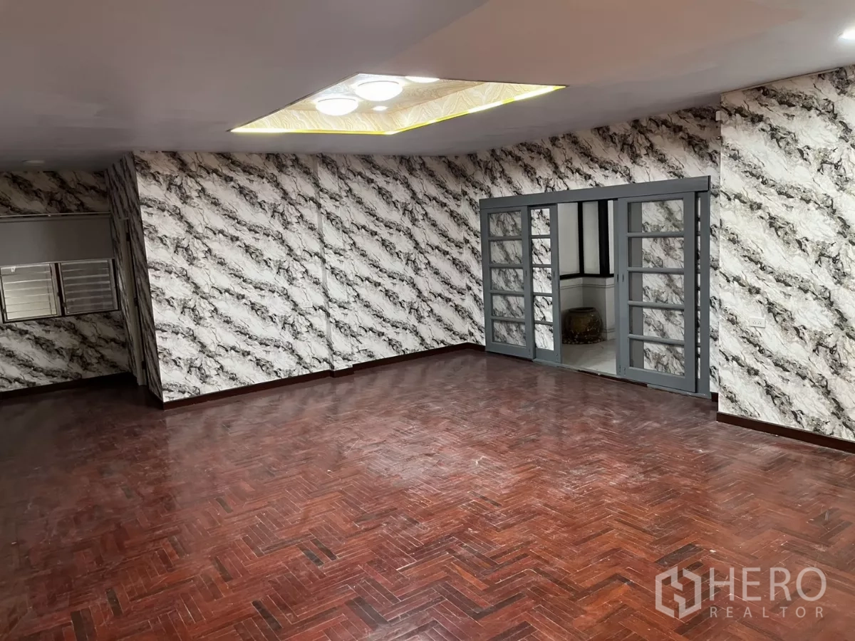 บ้าน ให้เช่าในWatthana, Bangkok - ห้องนั่งเล่นขนาดใหญ่ ผนังลายกราฟิก เพดานฝ้าซ่อนไฟ และประตูกระจกบานเลื่อน.