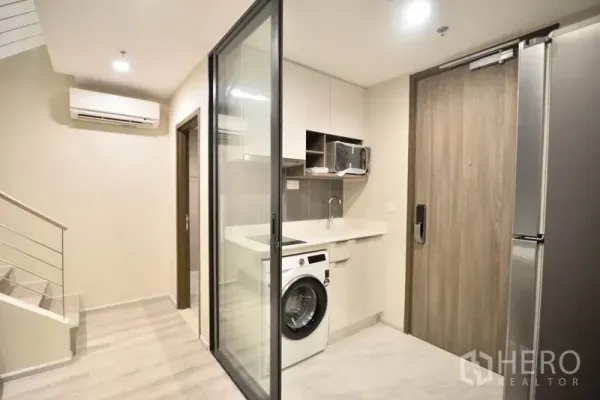 公寓 出租在Huai Khwang, Bangkok - 入户空间与玻璃隔断小厨房，带洗衣机和木质入户门的现代公寓