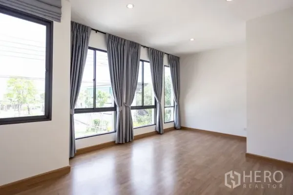 ทาวน์เฮาส์ ให้เช่าในBang Phli, Samut Prakan - ห้องกว้างมุมกระจกบานใหญ่ ติดผ้าม่านสีเทา พื้นไม้