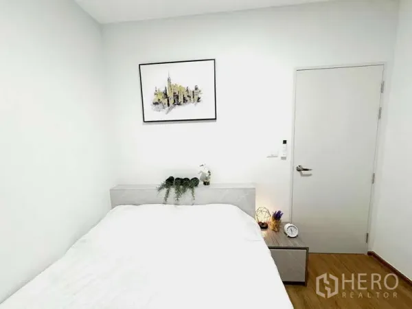 ทาวน์เฮาส์ ให้เช่าในBang Phli, Samut Prakan - ห้องนอนอบอุ่น มีเตียง โต๊ะข้างเตียง และภาพแขวนผนัง