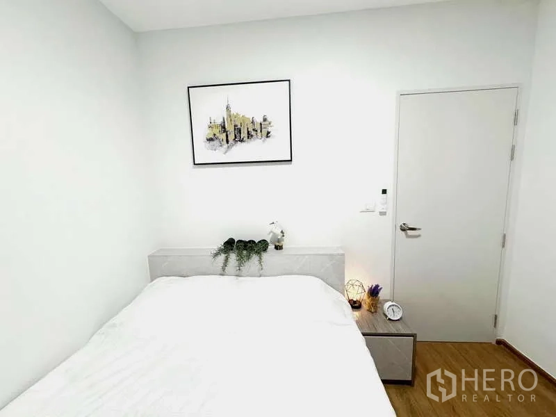 ทาวน์เฮาส์ ให้เช่าในBang Phli, Samut Prakan - ห้องนอนอบอุ่น มีเตียง โต๊ะข้างเตียง และภาพแขวนผนัง