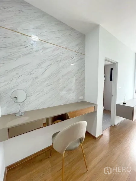 Townhouse for rent in Bang Phli, Samut Prakan - Vanity and study nook with marble accent wall and upholstered chair.