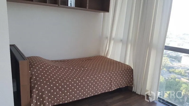 Condominium for rent or sale in Phra Khanong, Bangkok - Cozy second bedroom with single bed, built-in shelving and full-height windows overlooking the city.