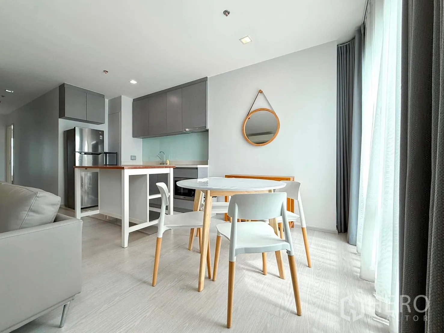 Condominium for rent in Khlong Toei, Bangkok - Dining nook with round table near balcony and modern gray kitchen.