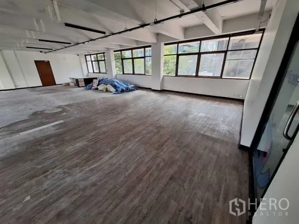 Office Space for rent in Watthana, Bangkok - Large open-plan office with wood-look floors, long windows and exposed ceiling beams.
