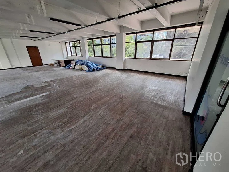 Office Space for rent in Watthana, Bangkok - Large open-plan office with wood-look floors, long windows and exposed ceiling beams.
