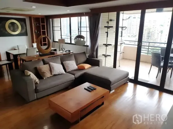 คอนโด ให้เช่าในWatthana, Bangkok - ห้องนั่งเล่นแบบเปิดโล่ง โซฟาเข้ามุมสีเทา พื้นไม้ และประตูกระจกบานเลื่อนออกสู่ระเบียงวิวเมืองกว้าง