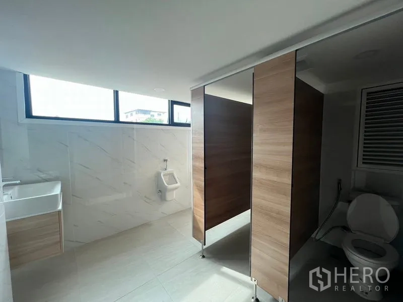 Office Space for rent or sale in Wang Thonglang, Bangkok - Restroom with wood-paneled stalls, urinal, sink and daylight windows.